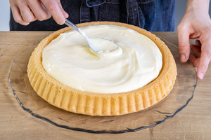 Puddingcreme auf dem Tortenboden der Erdbeer-Pudding-Torte verteilen