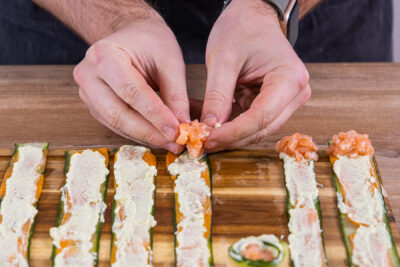 Lachs auf das Gurkensushi verteilen und zusammenrollen