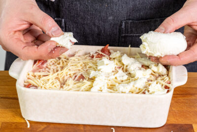 Käse über dem Cannelloni-Auflauf verteilen