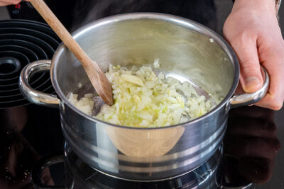 Zwiebel und Knoblauch zu geschmolzenen Butter in den Topf geben