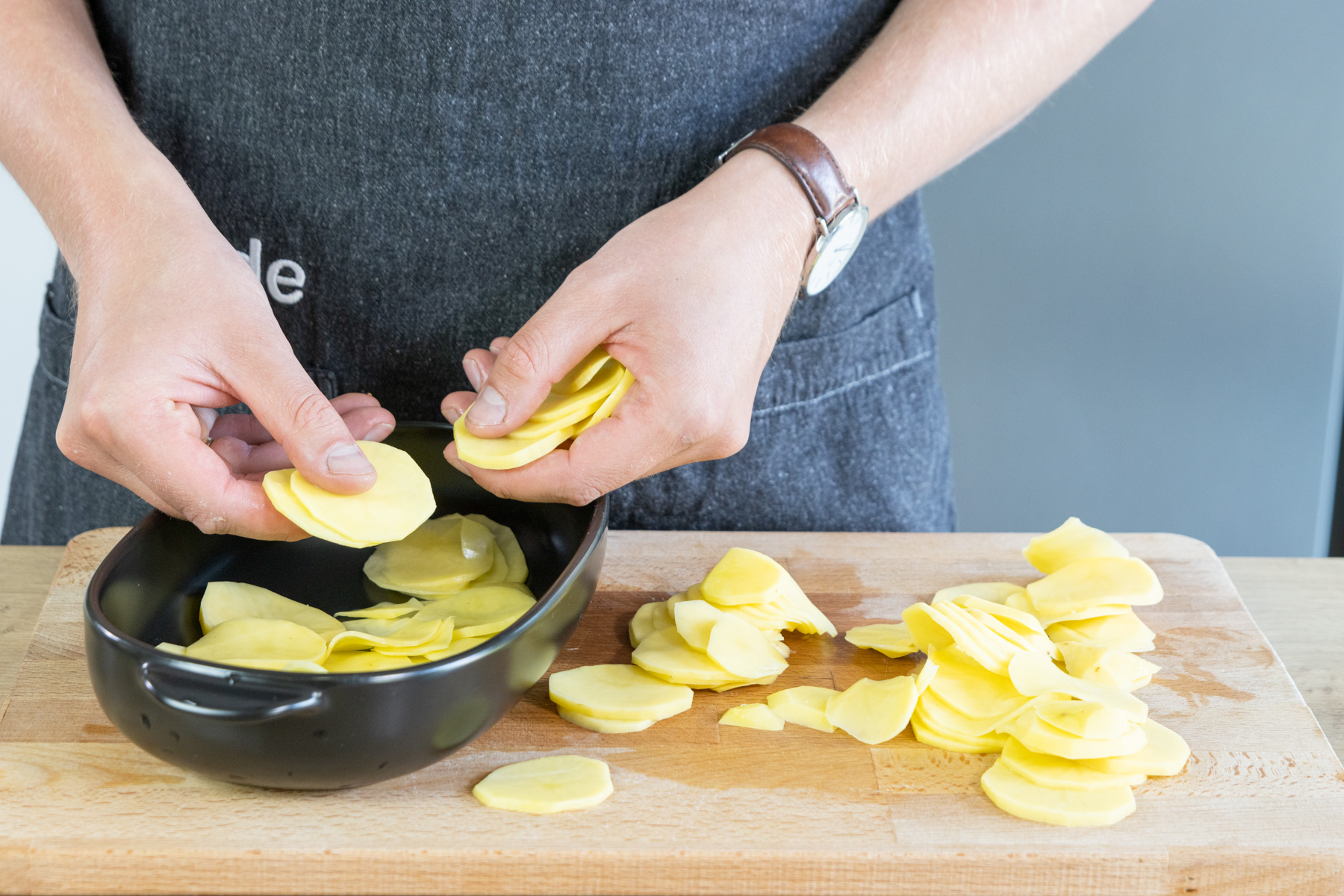 Kartoffelscheiben in die Auflaufform schichten