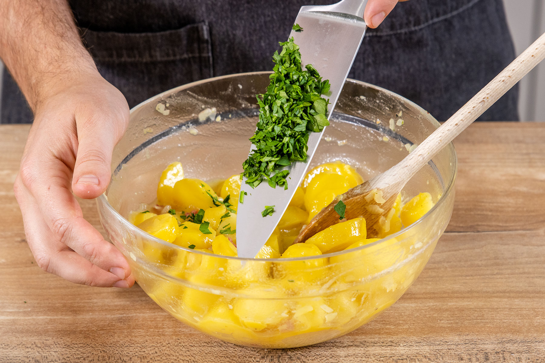 Petersilie zu dem klassischen Kartoffelsalat mit Brühe geben