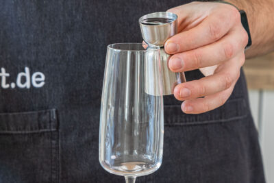 Cassis in ein Glas geben