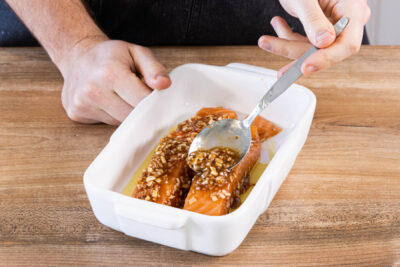 Lachs in Teriyaki-Marinade in eine Auflaufform geben und im Ofen garen
