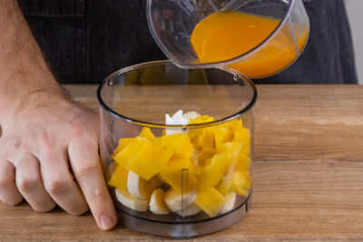 Mango-Saft zu der Mango und Banane geben