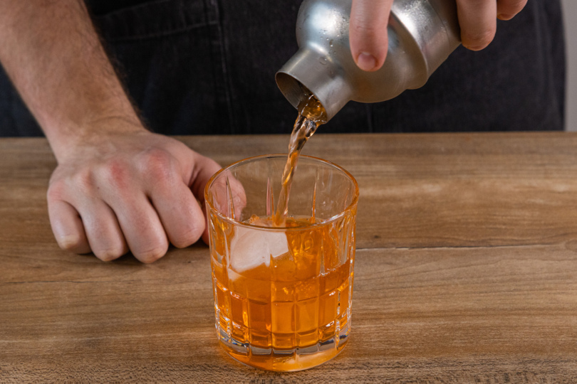 Negroni Cocktail in ein Tumbler-Glas füllen