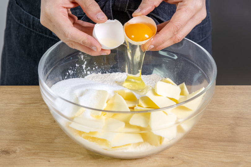 Eier zu Zucker, Butter, Salz und Mehl in die Schüssel geben