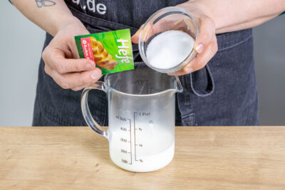 Zucker und Hefe zur warmen Milch geben