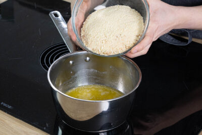 Kekskrümel in geschmolzene Butter einrühren