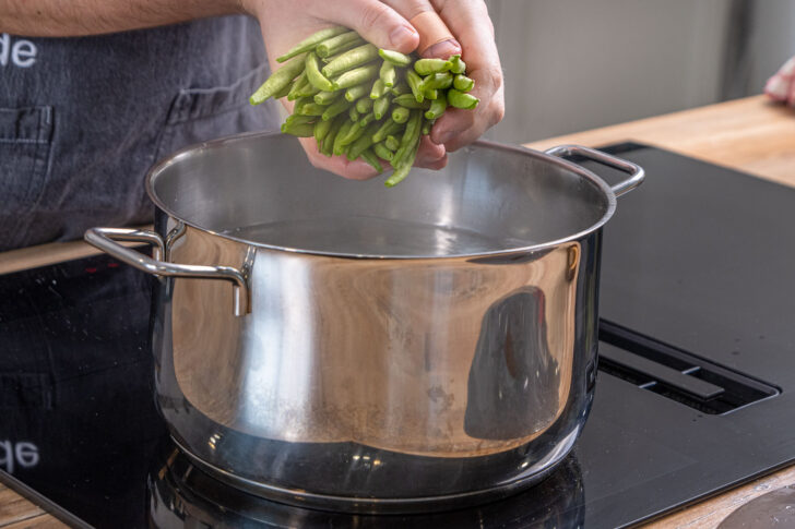 Wasser zum Kochen bringen und Gemüse hineingeben