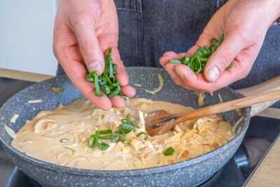 Frühlingszwiebel zur Sahne-Sauce geben