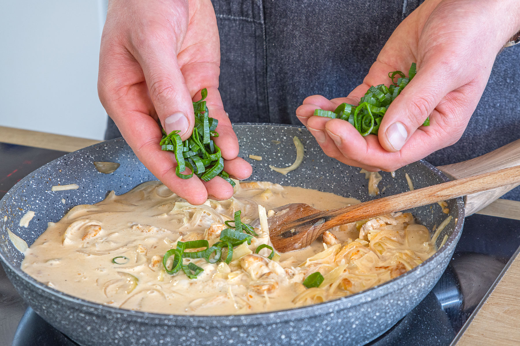 Frühlingszwiebel zur Sahne-Sauce geben