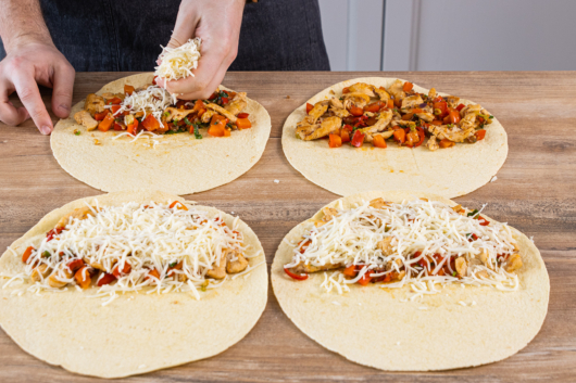 Quesadillas mit Hähnchen mit geriebenen Käse bestreuen