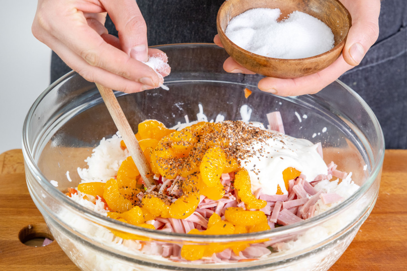 Reissalat mit Mandarinen mit Salz würzen
