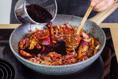 Rotwein zu den Zwiebeln gießen