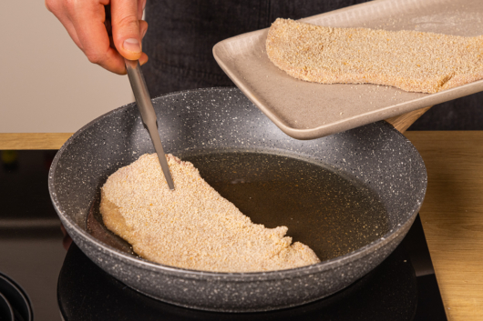 panierte Schnitzel in die Pfanne geben