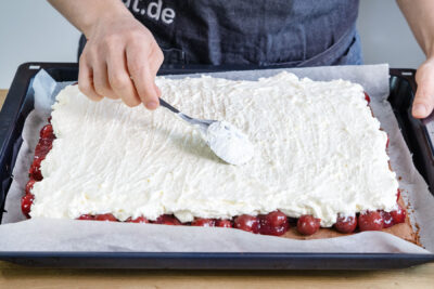 Schwarzwälder Kirschtorte vom Blech mit der Sahnecreme bestreichen