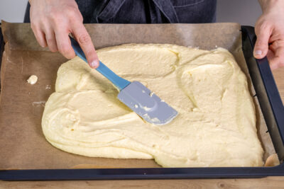 Teig des Selterwasserkuchen auf dem Backblech verstreichen