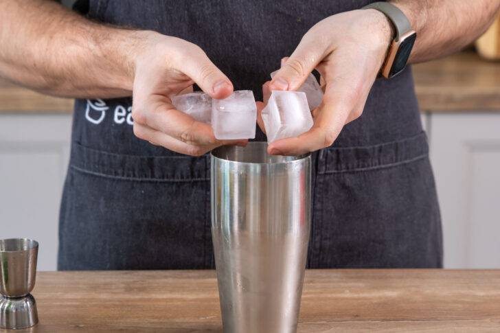 Eiswürfel in Cocktailshaker geben