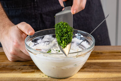 gehackte Kräuter zur Sour Cream geben