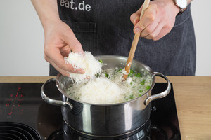 Parmesan in das Erbsen-Risotto geben