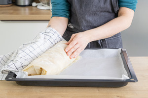 Apfelstrudel auf das Blech rollen