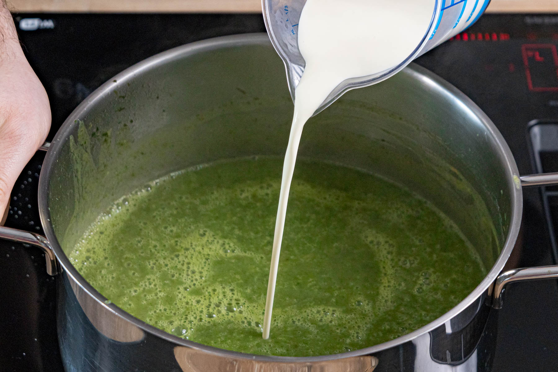 Sahne zur pürierten Bärlauchsuppe geben
