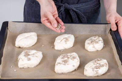Dinkelbrötchen ohne Hefe mit Sonnenblumenkernen bestreuen