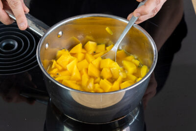 Mango, Maracujafleisch und Maracujasaft im Topf kochen