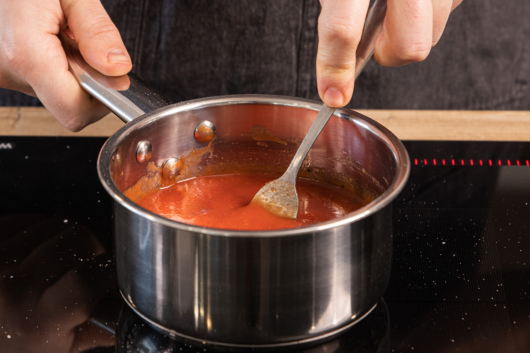 die passierten Tomaten in einem Topf zum Kochen bringen
