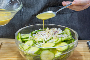 Essig-Öl-Dressing über Gurken geben