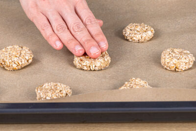 Haferflockenkekse mit Banane auf dem Backblech verteilen