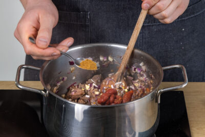 Gewürze und Tomatenmark zum Rindfleisch geben
