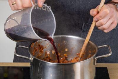 Rotwein in Topf gießen