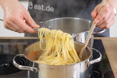Pasta in die Sauce geben