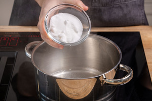 Zucker zum Wasser in den Topf geben