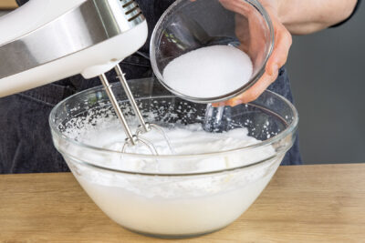 Zucker in Eischnee einrieseln lassen