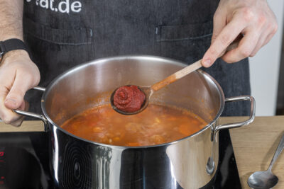Tomatenmark zur serbischen Bohnensuppe geben