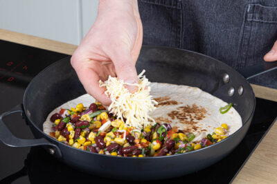 Füllung und Käse auf dem Tortilla verteilen