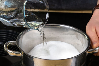 Zucker und Wasser in Topf geben