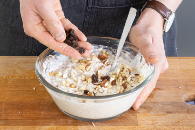 Bircher Müsli mit Joghurt mit Sultaninen und Nüssen verfeinern
