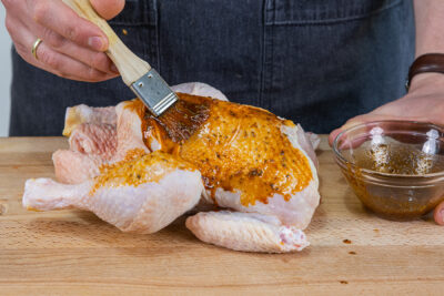 Das Brathähnchen mit der Marinade bestreichen