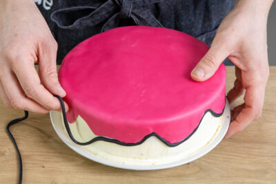 schwarzen Fondantstrang an der Kante der Pinken Fondantdecke anbringen