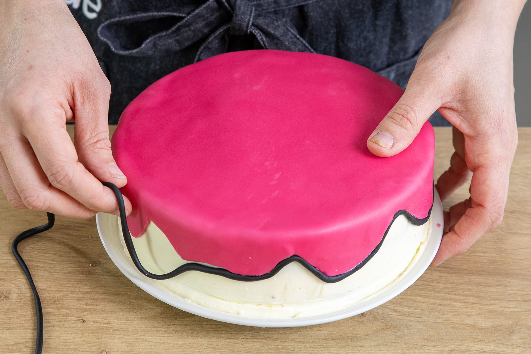 schwarzen Fondantstrang an der Kante der Pinken Fondantdecke anbringen