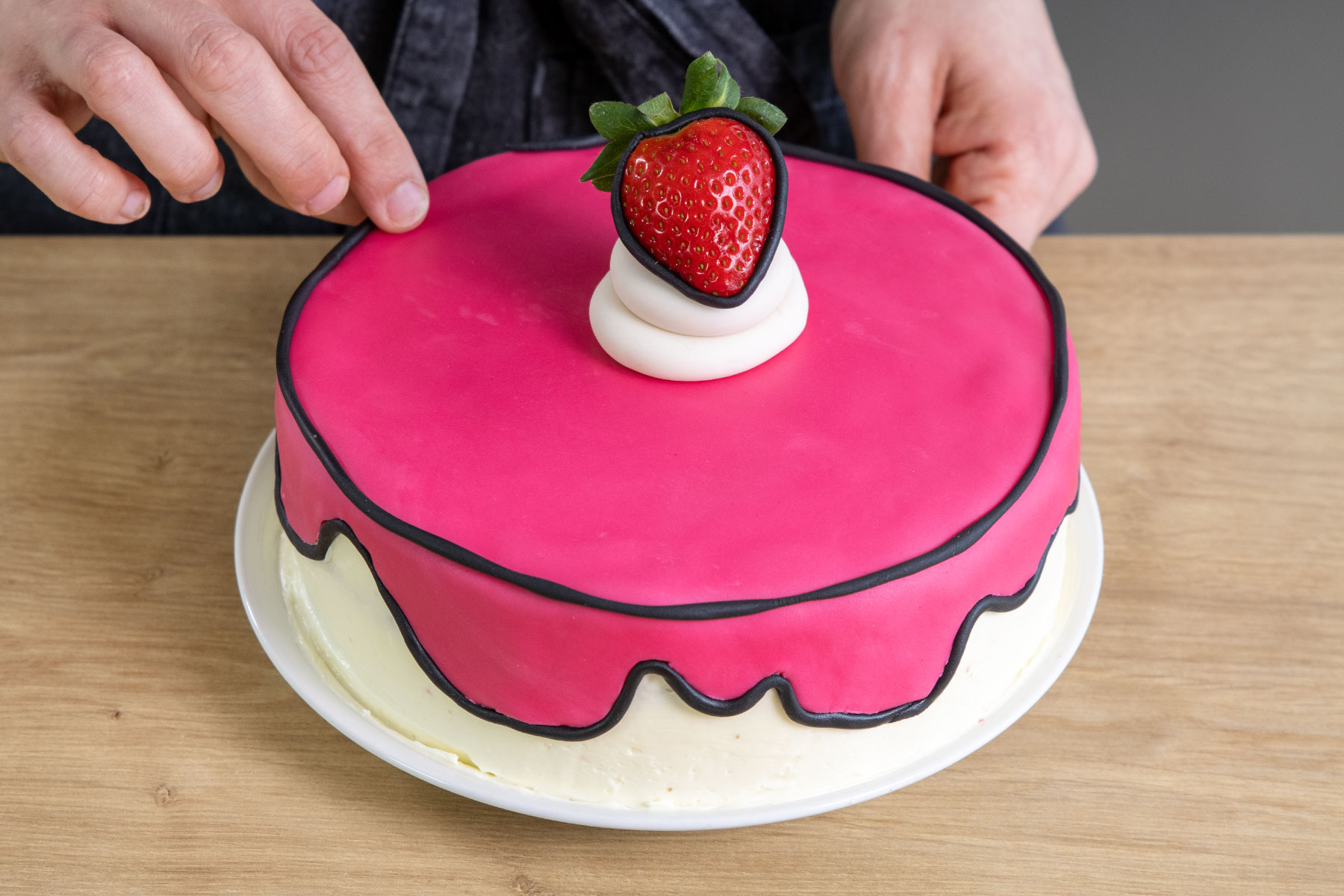 schwarze Fondantstränge an der Comic-Torte anbringen