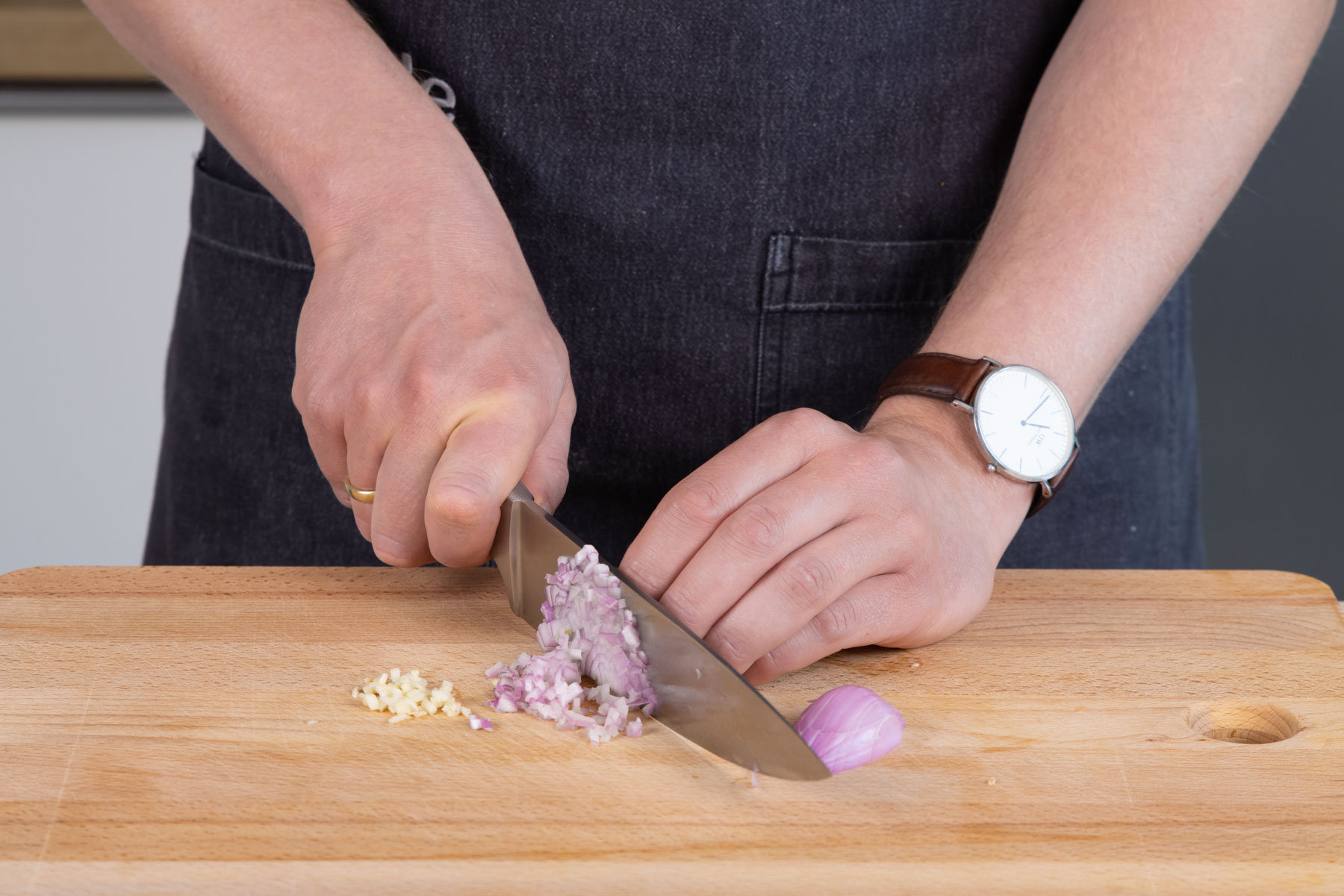 Die Zwiebel und den Knoblauch für das Rucola-Dressing schneiden.