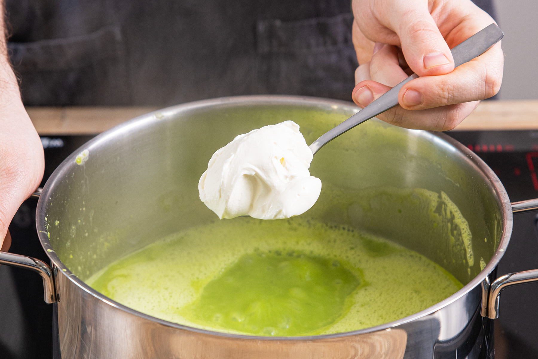 Crème fraîche in die Erbsencremesuppe geben