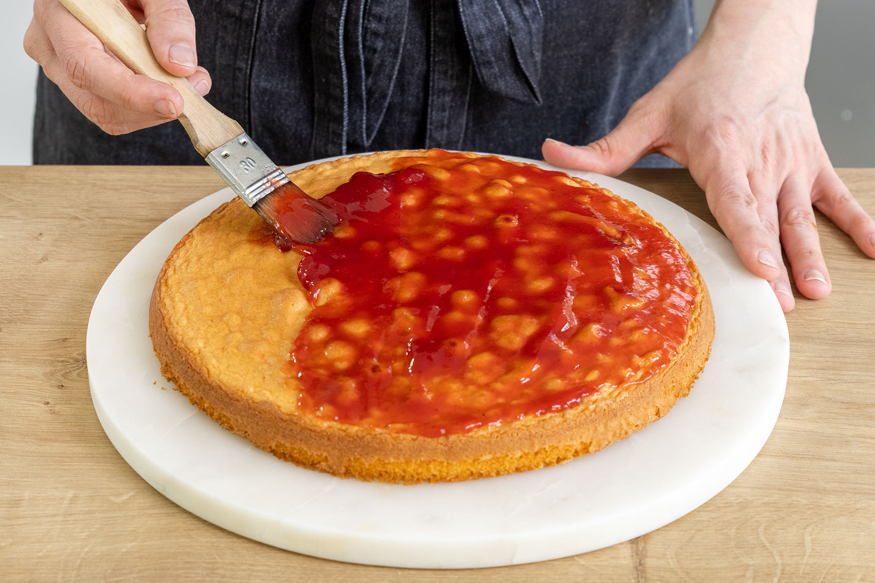 Boden der Erdbeer-Quark-Torte mit Erdbeermarmelade bestreichen
