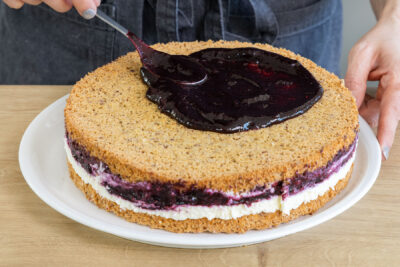 Blaubeerkompott auf der Blaubeertorte verteilen