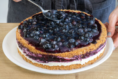 Heidelbeerguss auf der Blaubeertorte verteilen